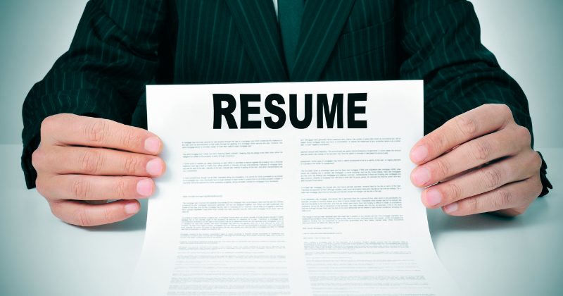 A man holding a paper with the word resume utilizing employee referral software.
